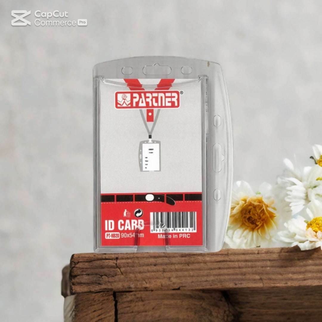 A Family Book Shop Partner ID Card Case, a transparent vertical badge holder with floral packaging and a red "Partner" label, sits on a wooden surface surrounded by white and yellow flowers.