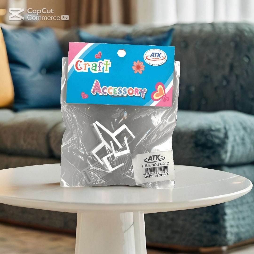 The ATK Craft Accessories Miniature Furniture Set - White by Family Book Shop, featuring a blue and pink heart-themed label, sits elegantly on a small white table against a blurred grey couch with colorful cushions, adding a cozy touch.